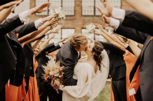 newlyweds kissing under an arc of arms